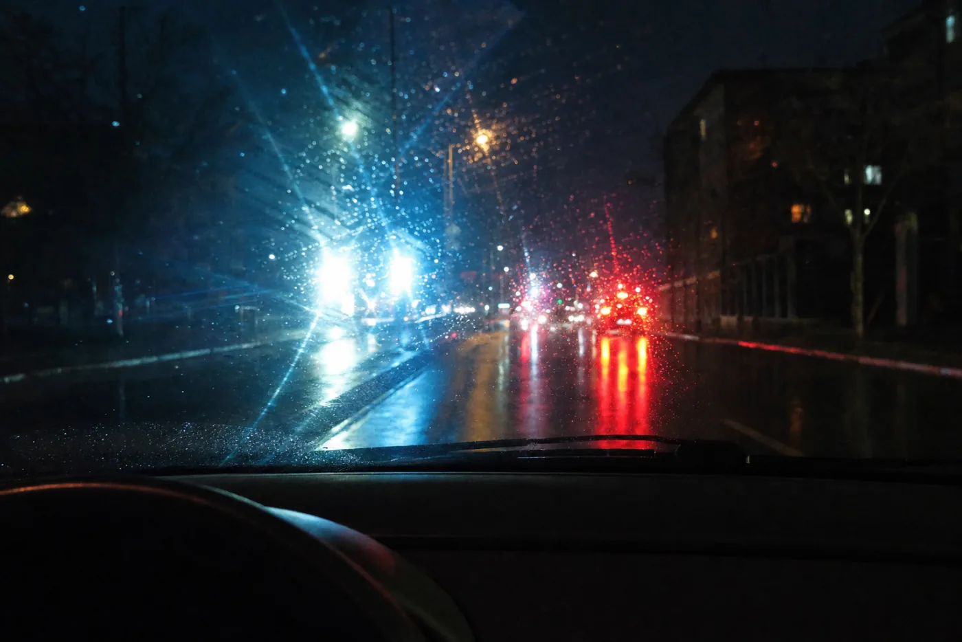 Vista desde el interior de un carro de noche con faros que deslumbran